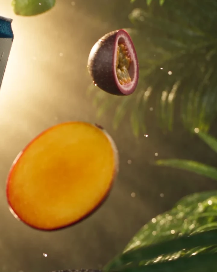 A halved mango and a passion fruit floating in the sun