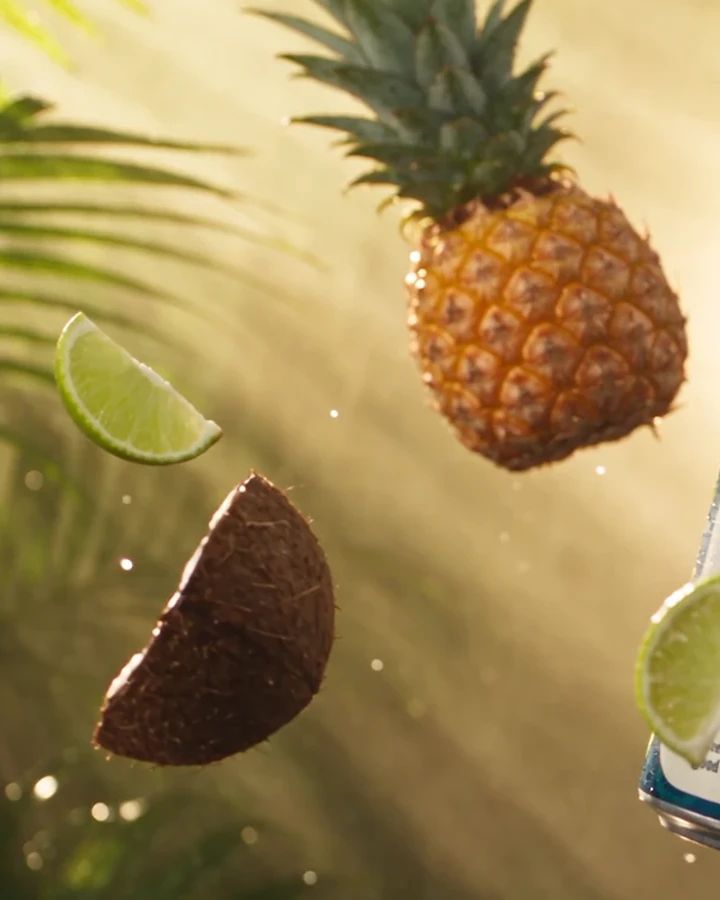 A pineapple and a split coconut floating among palm leaves
