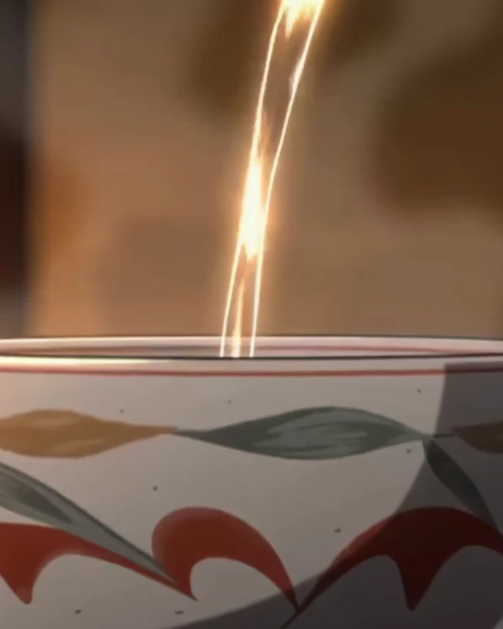A thin stream of hot water falling into a painted tea bowl