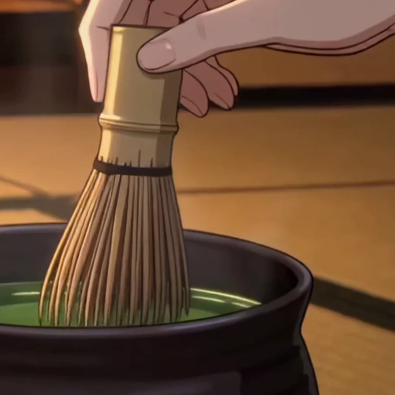 A bamboo whisk soaking in a dark pot of warm water